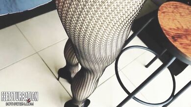 Shoe dangling off toes over sheer fishnets and sky high heels