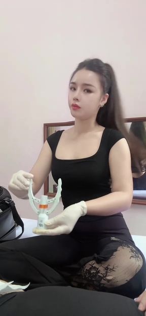 Slim Vietnamese nurse sits at desk in uniform, professionally focused