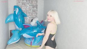 Alla rides on inflatable toys and inflates two balloons with her mouth and pops them with her nails and shows off her bare feet