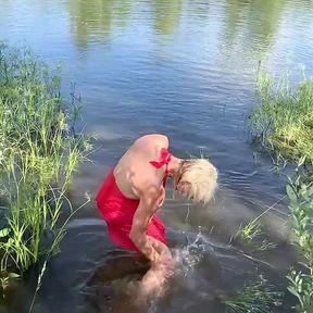 Swimming in lake in coral color summer dress and white sneakers. Wet dress. Wetlook transgirl