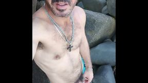 esperando um puto para deixar ele duro nas pedras de uma praia de nudismo.