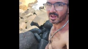 esperando um puto para deixar ele duro nas pedras de uma praia de nudismo.