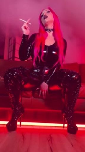 Pink haired Luvie Doll smoking EVE 120s cigarette in a PVC catsuit looking like the devil with nails