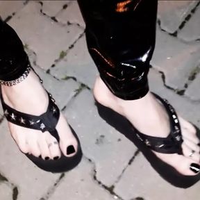 crossdresser on a public street in latex leggings and sexy platform flip flops