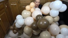 women in red vinyl outfit and black vinyl jacket pops balloons with fingernails and sitting on them