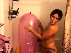 Tattooed babe teasing with a big balloon in the shower