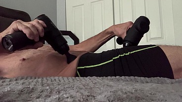 Solo Male Massaging Pelvis for therapeutic release with 2 Percussion gun massagers in shorts then boxer briefs bulge