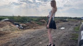 A girl in very high-heeled shoes walks through the mud and gets her sexy suede shoes dirty