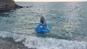 Alla rides a blue transparent whale in the sea and wears a blue inflatable vest