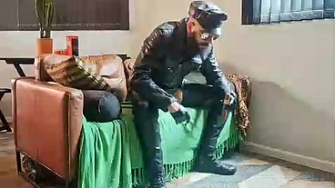 Mestre fumando um charuto na sala de estar vestido de couro e chama seu submisso obediente