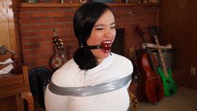 Raven Lynette tied during an undercover mission, first gagged with ballgag then mouth heavily stuffed and wraparound gagged with clear tape