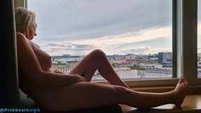 Naked hot MILF sitting on the windowsill and playing with her pussy