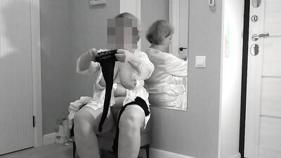 A mature, fat milf with big, saggy tits is changing clothes in front of the mirror.