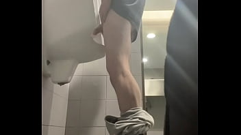 2 boys in sneakers having fun at public toilets&#039_ urinal