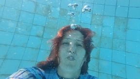 Swimming and blowing bubbles underwater while wearing a long sleeve