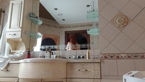 A Charming Woman Is Preening in the Bathroom in Front of a Mirror