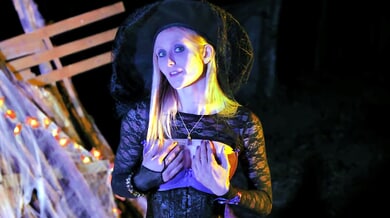 Blonde witch Kelly Dolls casts a spell under glowing Halloween lights