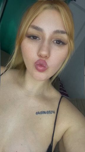 Blonde woman in a black tank top making a duck face