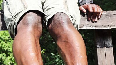 Kinky black guy rubs oil on his feet and teases outdoors