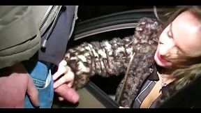 Slutty blonde with red lipstick on her lips is sucking dick through a car window