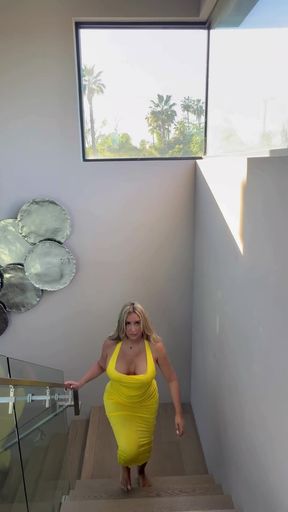 Blonde woman in yellow dress walking down stairs