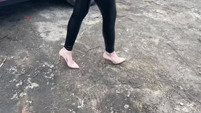 A girl in high-heeled shoes walks through liquid mud, into which her heels sink completely