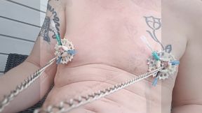 6 needles through the nipples stretched by plastic flower ring with holes on the terrace outside