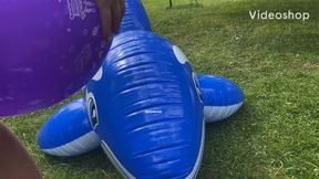 2 girls popping balloons on an inflatable whale