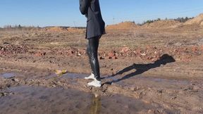A girl in fashionable white sneakers walks in the mud (short version)