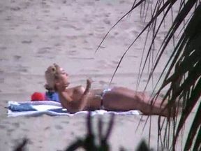 Spying on one busty blonde babe taking a sunbath on beach topless