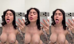 Tattooed woman licks lips while taking mirror selfie