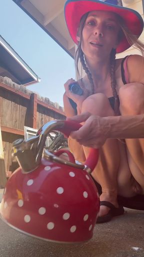 Woman in cowboy hat pouring water from red kettle