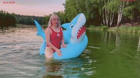 Swimming on a large inflatable shark ring on a lake