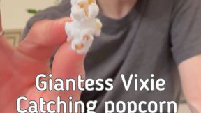 Giantess Vixie catching popcorn in her giant mouth with Tiny Man inside