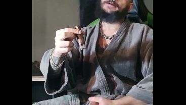Tattoed daddy smoking a cigar in his smoky robes