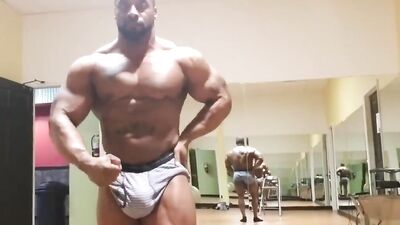 Big strong black dude is flexing those muscles in front of the mirror