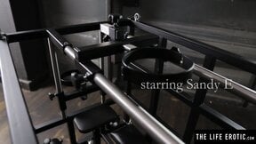 Kinky blonde Sandy E fingers her pussy in a BDSM cage