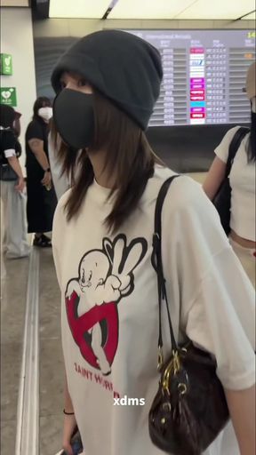 Woman in black beanie and white t-shirt walking through airport