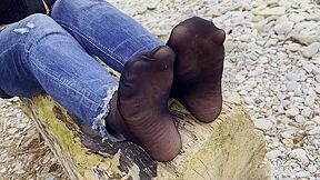 Feet In Black And Grey Nylon Socks Wiggling Toes At The Seashore