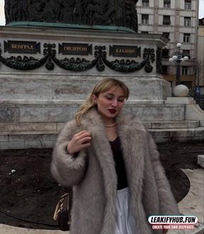 Woman in fur coat standing near statue