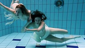 Two captivating young white girls under water in the pool