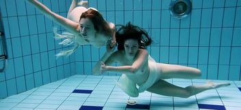 Two captivating young white girls under water in the pool