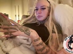 Inked Blonde Bombshell Holding Toys in Bed