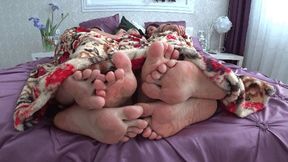 Three pairs of legs flirting under the blanket b