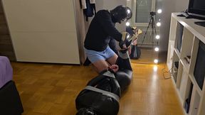 girl in leather catsuit, high heels and latex mask is gagged and in tape bondage for her first time