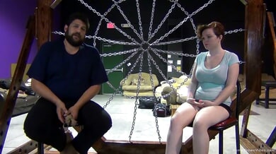 Redheaded woman bound in rope and chains for intense BDSM teasing session