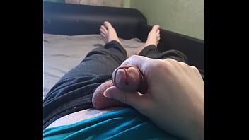 Guy in a blue T-shirt jerks off his dick lying on the bed