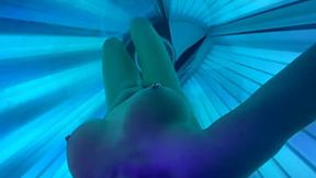 Hot babe plays with her big tits in a tanning bed