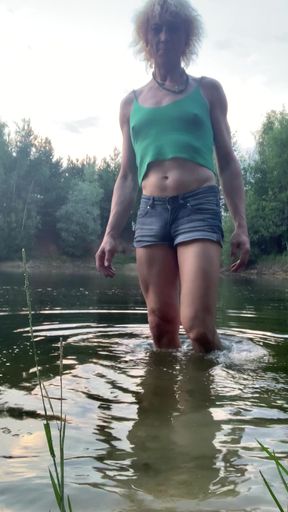Trans girl swimming in the lake in shorts and green top. Wetlook at th lake.