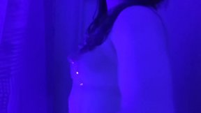 Trans person in bikini strips, showers, and plays under black light